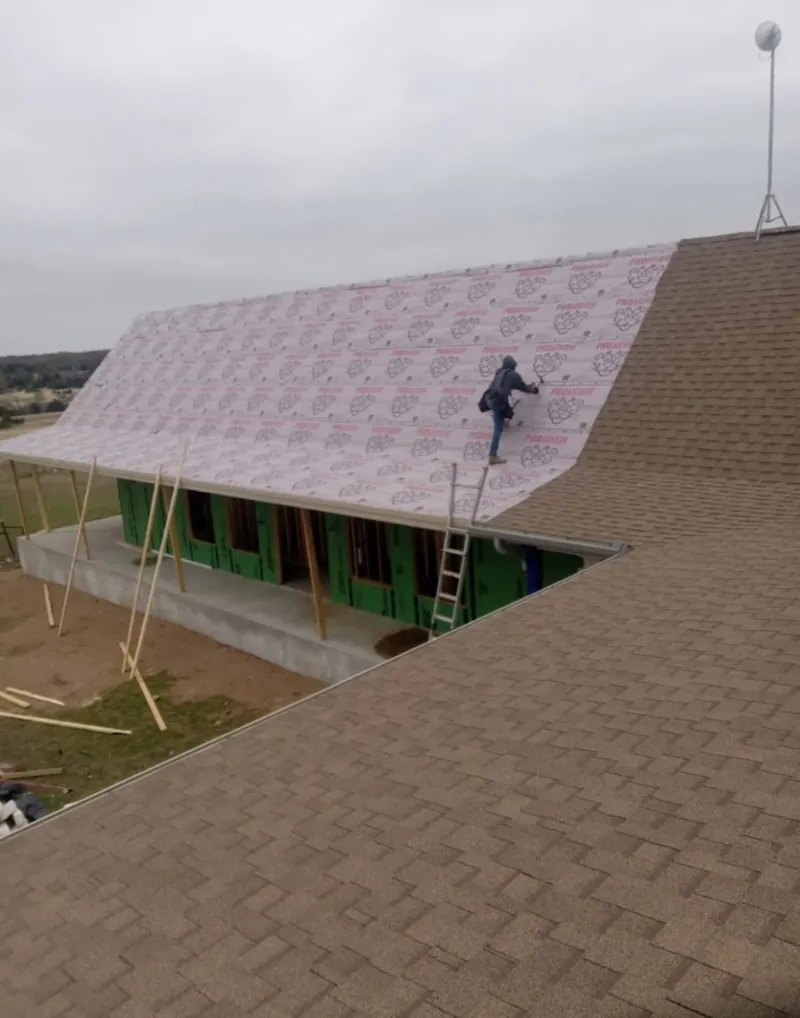 Worker preparing underlayment for a metal roof installation in Dickson